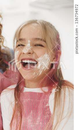 Child smiles with flour on face during cooking activity at home in the kitchen 136734972