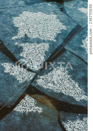 Cold water and cracked ice in a winter scene showing patterns and reflections near a body of water on a cloudy day in the afternoon Cold water and cracked ice in a winter scene showing patterns and reflections near a body of water on a cloudy day in the afternoon 136735030