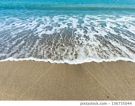 Waves rolling onto sandy beach with clear blue water on sunny day at the coast Waves rolling onto sandy beach with clear blue water on sunny day at the coast 136735044