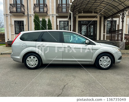 Silver minivan parked outside a building with a covered entrance on a cloudy day Silver minivan parked outside a building with a covered entrance on a cloudy day 136735049