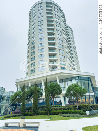 Building stands tall near park with green trees and open space in city, showing modern architecture and urban setting in daylight hours Building stands tall near park with green trees and open space in city, showing modern architecture and urban setting in daylight hours 136735101