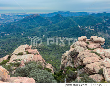 View from rocky peaks overlooking green hills and distant coastline in the midday light showing a landscape with trees and mountains View from rocky peaks overlooking green hills and distant coastline in the midday light showing a landscape with trees and mountains 136735102