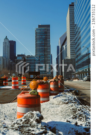 Construction work takes place in a busy urban area with tall buildings and clear sky at midday Construction work takes place in a busy urban area with tall buildings and clear sky at midday 136735112