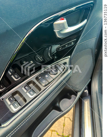 Inside a car showing the door control panel and speaker location at a parking spot during daytime Inside a car showing the door control panel and speaker location at a parking spot during daytime 136735119