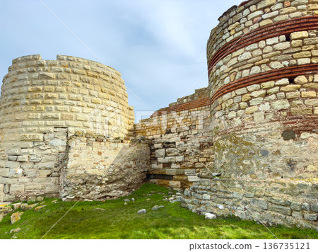 Ruins of an ancient stone structure located in a historical site with visible layers and features under a cloudy sky Ruins of an ancient stone structure located in a historical site with visible layers and features under a cloudy sky 136735121