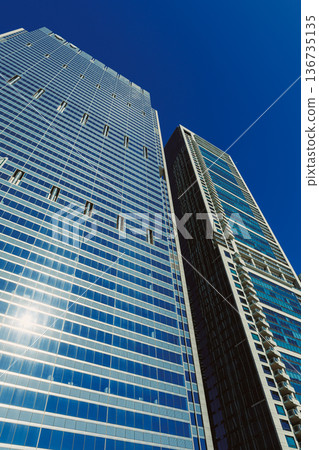 Tall buildings reach up to the clear blue sky in a busy urban area during bright daylight hours with no clouds present Tall buildings reach up to the clear blue sky in a busy urban area during bright daylight hours with no clouds present 136735135