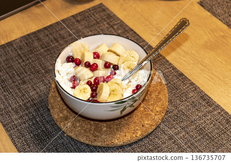 Cottage cheese mixed with bananas and cranberries in a bowl 136735707