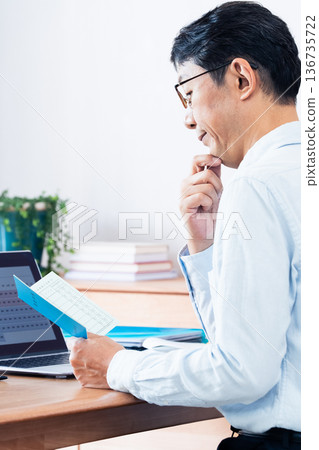 一位中年男子一邊看著他的退休金手冊一邊思考。 136735722