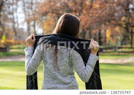 Woman with scarf in autumn park, back view Woman with scarf in autumn park, back view 136735747