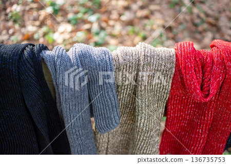 Knitted scarves hanging outdoors in black, gray, beige and red Knitted scarves hanging outdoors in black, gray, beige and red 136735753