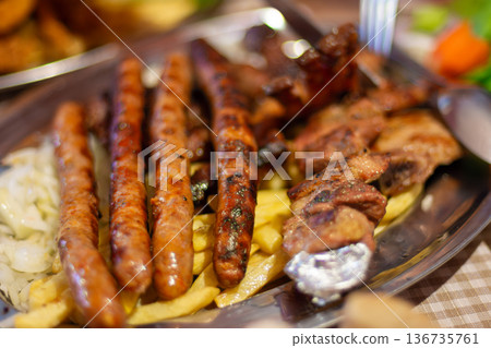 Mixed grilled meats and sausages with fries on tray Mixed grilled meats and sausages with fries on tray 136735761