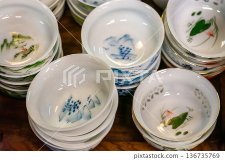 Stacked porcelain tea cups with hand-painted bird designs Stacked porcelain tea cups with hand-painted bird designs 136735769