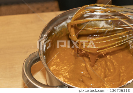 A person whisks the sauce in a pot A person whisks the sauce in a pot 136736318