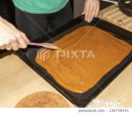 Person spreads, brown, heavy, sugary cream on a baking tray 136736431
