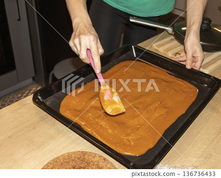 Person spreads, brown, heavy, sugary cream on a baking tray Person spreads, brown, heavy, sugary cream on a baking tray 136736433