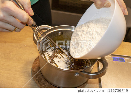A person whisks the sauce in a pot 136736749