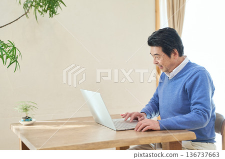 Senior Asian man using a computer Senior Asian man using a computer 136737663