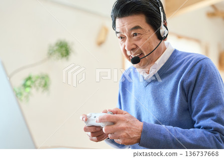 一位年長的亞洲男子正在玩電腦遊戲 136737668