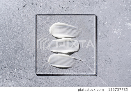 A sample of white body cosmetics on a glass square. Grey background. 136737785