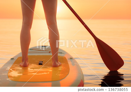 Young woman walking on stand up paddle sup boards by the sea during summer vacation Young woman walking on stand up paddle sup boards by the sea during summer vacation 136738055