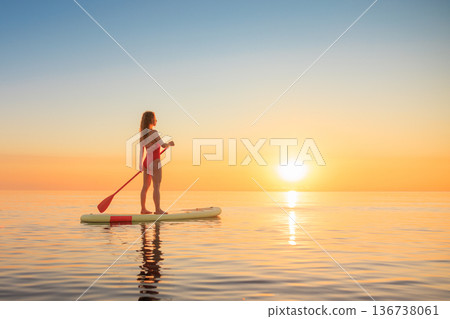 Young woman walking on sup board by the sea during summer vacation Young woman walking on sup board by the sea during summer vacation 136738061