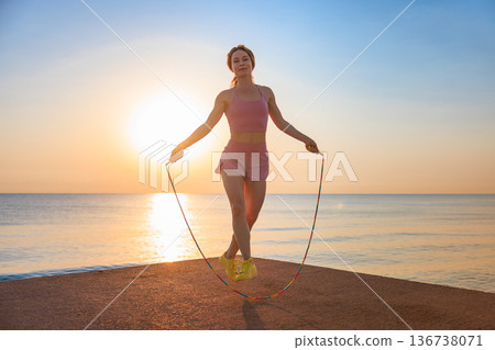 Fit woman jumping rope at the beach during summer vacation Fit woman jumping rope at the beach during summer vacation 136738071
