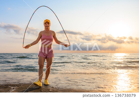 Fit woman jumping rope at the beach during summer vacation Fit woman jumping rope at the beach during summer vacation 136738079