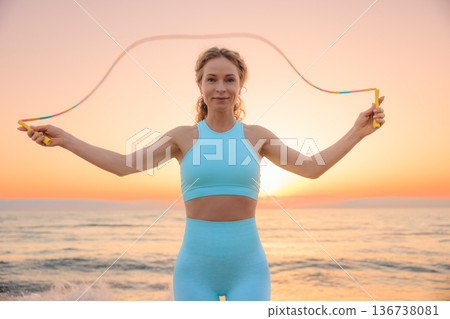 Fit woman jumping rope at the beach during vacation. Healthy lifestyle and summer sport concept 136738081