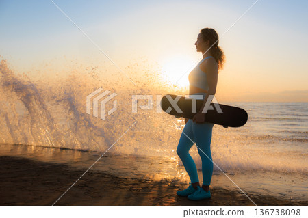 Fit young woman is posing against sea background. Sporty female with skateboard on the seaside promenade. Fit young woman is posing against sea background. Sporty female with skateboard on the seaside promenade. 136738098