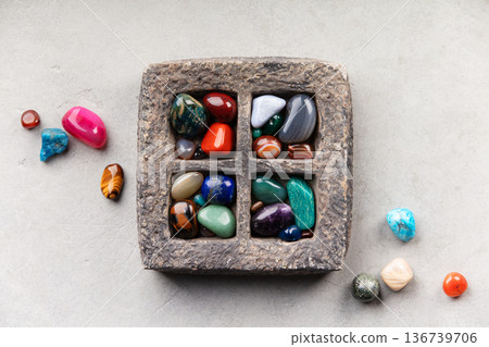 Colorful Tumbled Gemstones in Rustic Stone Tray on Light Surface Colorful Tumbled Gemstones in Rustic Stone Tray on Light Surface 136739706
