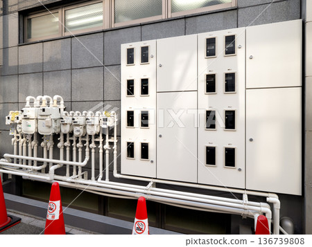Multiple gas meters and distribution panels line the exterior wall of the building 136739808