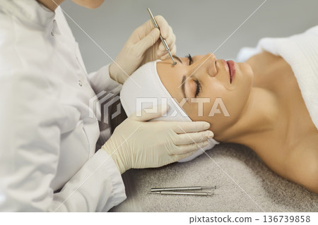 Esthetician performing blackhead extraction with tool during professional facial care Esthetician performing blackhead extraction with tool during professional facial care 136739858