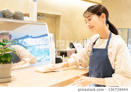 一位年輕的女員工在咖啡館擦拭櫃檯 136739944