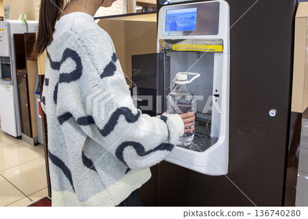 一名女子正在超市的飲水機接水。 136740280