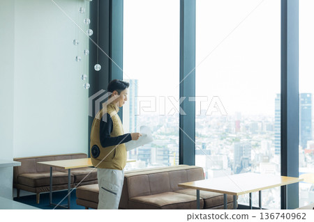 A male craftsman in an air-conditioned suit checking the site while looking at documents A male craftsman in an air-conditioned suit checking the site while looking at documents 136740962