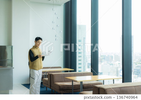 一位身穿空調服的男工匠正在檢查工地文件並進行檢查。 136740964