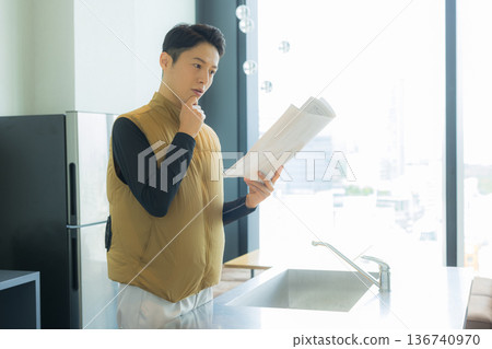 A male craftsman in an air-conditioned suit checking the site while looking at documents A male craftsman in an air-conditioned suit checking the site while looking at documents 136740970