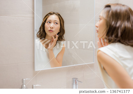 Young woman looking at a mirror 136741377