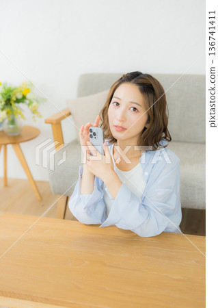 一個微笑的女人看著智能手機 136741411