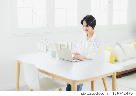 A woman watching a computer at home A woman watching a computer at home 136741470