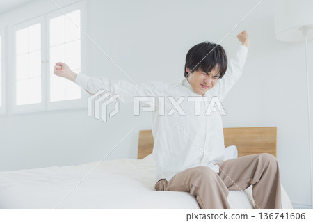 Young man relaxing in bedroom Young man relaxing in bedroom 136741606