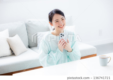 A woman who uses a smartphone in a room 136741721