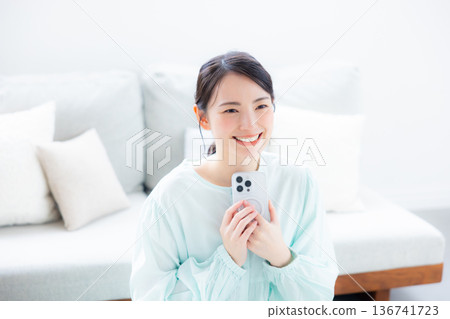 A woman who uses a smartphone in a room A woman who uses a smartphone in a room 136741723