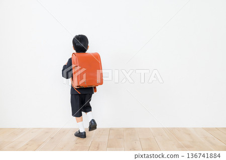 A boy in a suit carrying a school bag 136741884