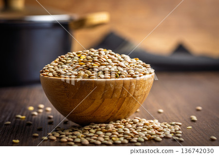 Uncooked green lentil in bowl on wooden table. Uncooked green lentil in bowl on wooden table. 136742030