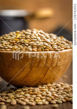 Uncooked green lentil in bowl on wooden table. Uncooked green lentil in bowl on wooden table. 136742031