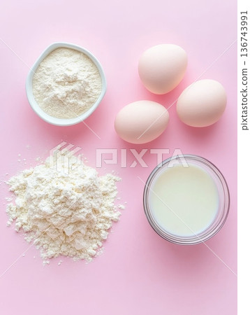 Baking essentials including flour, eggs, and milk arranged on a pastel pink background, showcasing the start of a culinary creation 136743991