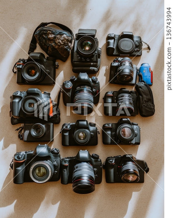 An array of professional digital cameras and lenses displayed on a light background, showcasing various models and equipment for photography enthusiasts 136743994