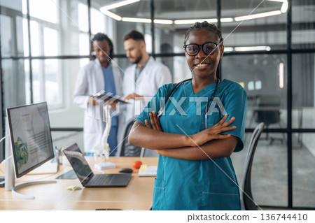 Woman in glasses is standing. Doctors are working in the office Woman in glasses is standing. Doctors are working in the office 136744410