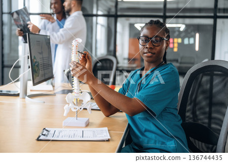 Education conception, showing human spine model. Doctors are working in the office Education conception, showing human spine model. Doctors are working in the office 136744435